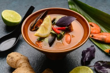 Arka planda bir kase baharatlı Tayland çorbası.