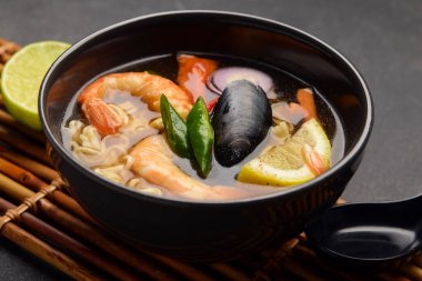 Arka planda bir kase baharatlı Tayland çorbası.