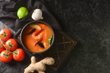 Arka planda bir kase baharatlı Tayland çorbası.