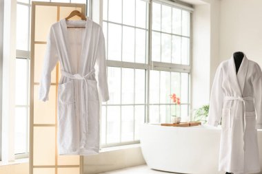 Havalı bir banyonun içinde pencereli bornozlar.