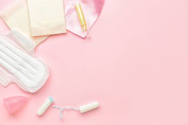 Pembe arka planda regl kupası, ped ve tampon.