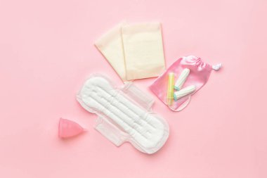 Pembe arka planda regl kupası, ped ve tampon.