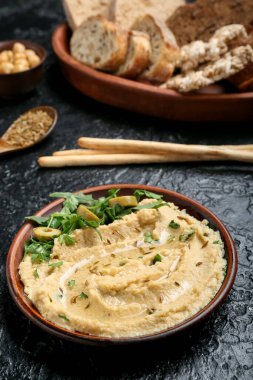 Koyu arkaplanda lezzetli humus olan kase, yakın plan.