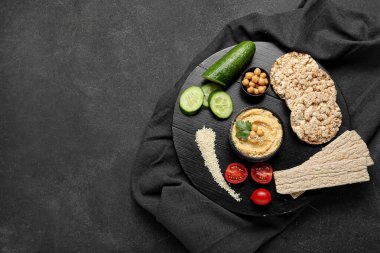 Lezzetli humus, kraker ve sebzelerle dolu bir kase.