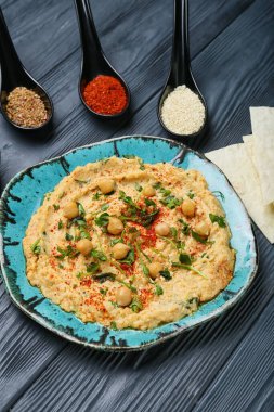 Lezzetli humus tabağı, pide ve baharatlar koyu ahşap arka planda