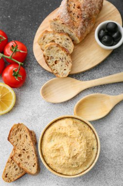 Lezzetli humus, gri arka planda ekmek ve zeytinli kase.