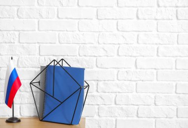 Rus bayrağı ve tuğla duvarın yanındaki masada dizüstü bilgisayarlarla dur.