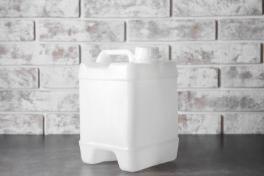 Tuğla duvarın yanındaki plastik bidon.