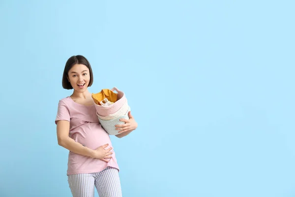 Jovem Grávida Segurando Cesta Com Roupas Bebê Fundo Azul — Fotografia de Stock