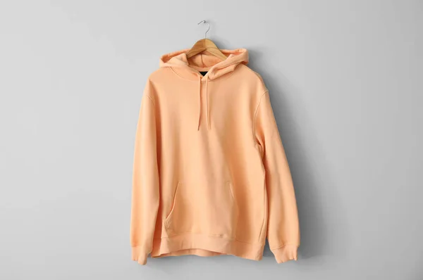 Stijlvolle Perzikkleurige Hoodie Hangend Aan Lichte Muur — Stockfoto