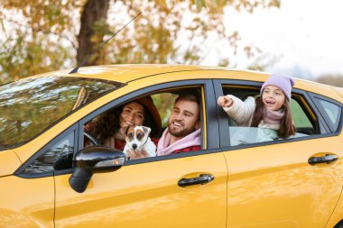 Küçük kızları ve sarı arabasında oturan sevimli köpekleri olan ebeveynler.