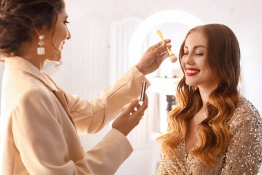 Makyaj sanatçısı güzellik salonunda güzel bir modelle çalışıyor.