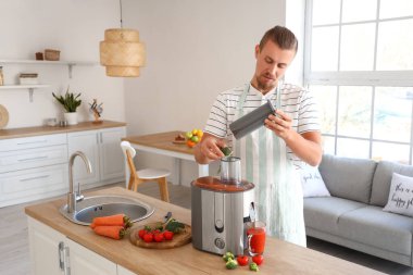 Genç adam mutfakta sağlıklı sebze suyu hazırlıyor.