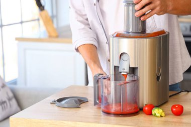 Genç adam mutfakta sağlıklı sebze suyu hazırlıyor.