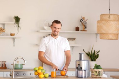 Genç adam mutfakta sağlıklı meyve suyu hazırlıyor.