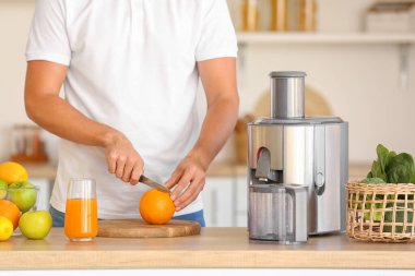 Genç adam mutfakta sağlıklı meyve suyu hazırlıyor.