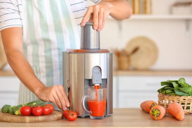 Genç adam mutfakta sağlıklı sebze suyu hazırlıyor.