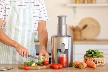 Genç adam mutfakta sağlıklı sebze suyu hazırlıyor.