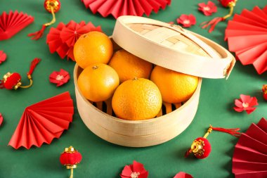 Renkli arkaplanda lezzetli mandalinalar ve Çin sembolleri olan bir kutu