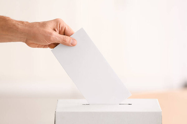 Голосование молодого человека возле урны для голосования