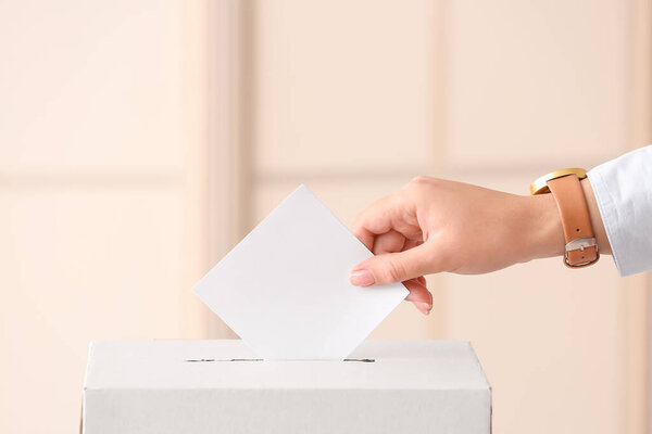 Голосование женщины возле урны для голосования