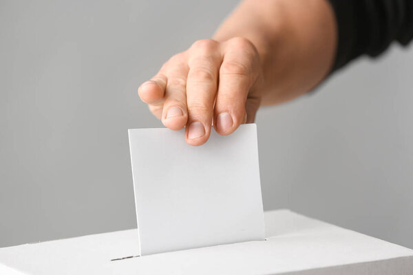 Голосование молодого человека возле урны для голосования