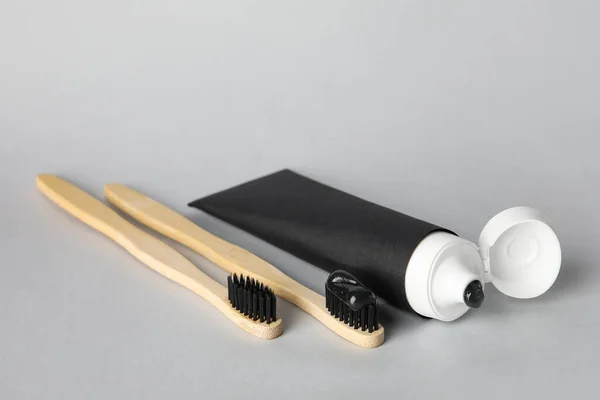 Tube Met Zwarte Tandpasta Bamboe Penselen Grijze Ondergrond — Stockfoto