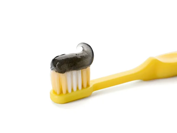 Žlutý Kartáč Černým Zubní Pastou Bílém Pozadí — Stock fotografie
