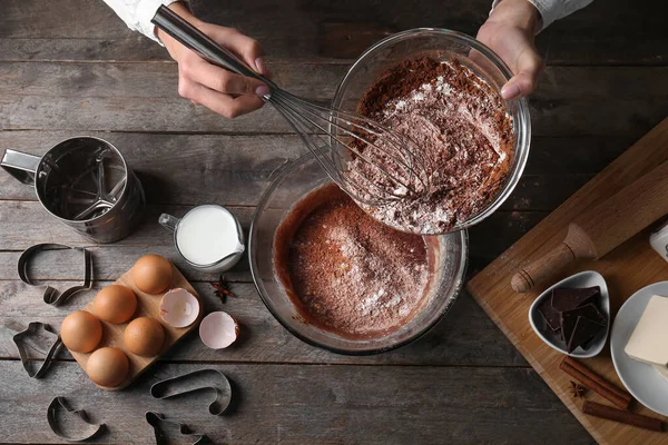 Tahta arka planda çikolata hamuru hazırlayan kadın