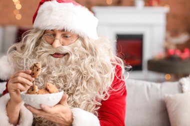 Noel Baba evde lezzetli kurabiyeler yiyor.