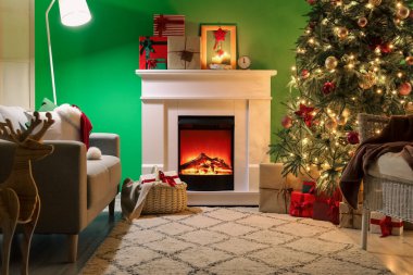 İçinde şömine, hediye kutuları ve büyük Noel ağacı olan oturma odası.