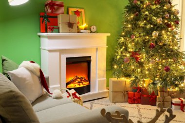İçinde şömine, hediye kutuları ve büyük Noel ağacı olan oturma odası.