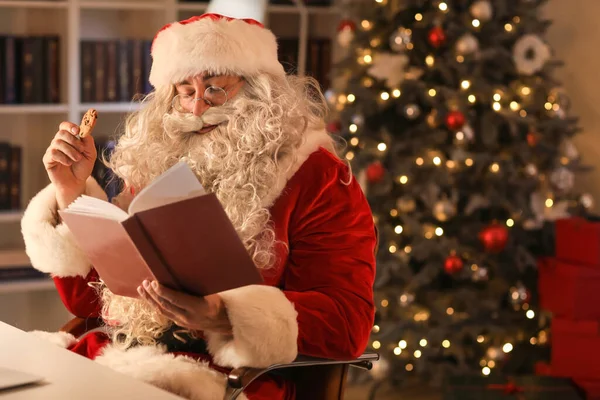Santa Claus Eating Tasty Cookies While Reading Book Home Evening — Stock Photo, Image