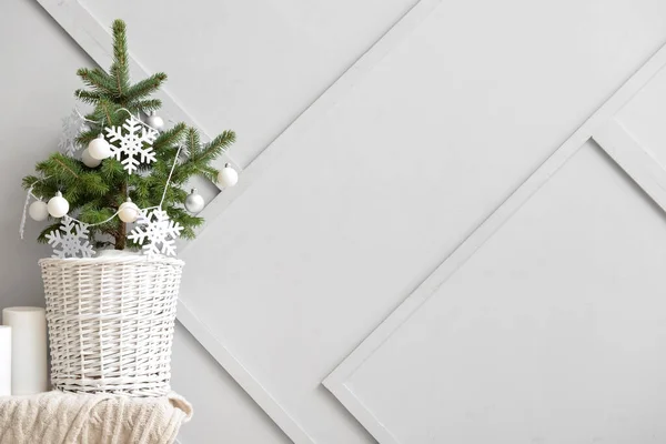 漂亮的圣诞树 篮子里挂着雪花和球 放在靠近轻墙的桌子上 — 图库照片