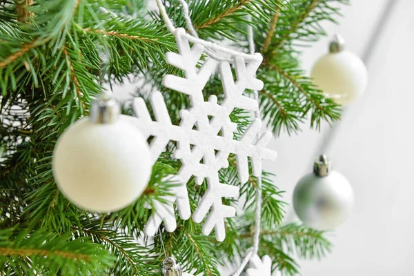 光の壁の近くの雪片やボールで飾られた美しいクリスマスツリー クローズアップ — ストック写真