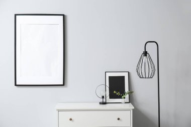 Çerçeveli çekmeceler ve lambalarla aydınlık duvarın yanında