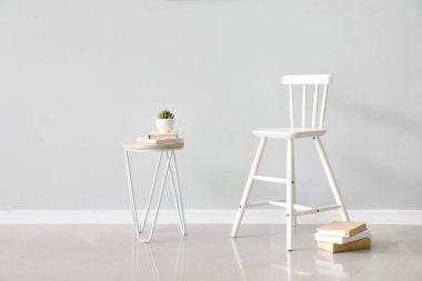 Beyaz koltuk ve masa, ışık duvarına yakın kitaplar.