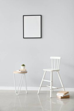 Beyaz koltuk ve masa, ışık duvarına yakın kitaplar.