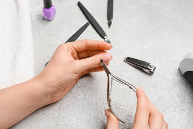 Genç kadın ışık masasında manikür yapıyor.