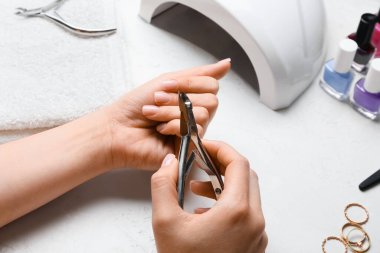 Işık masasında meme uçlarıyla manikür yapan kadın.