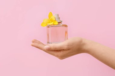Güzel manikürlü kadın eli ve arka planda parfüm şişesi.