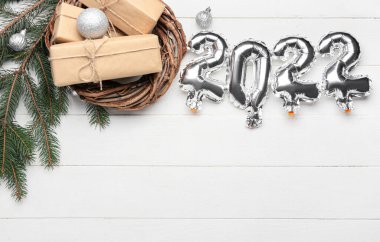 2022 şeklinde gümüş balonlar ve beyaz ahşap arka planda Noel dekoru.