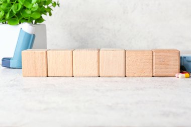 Boş tahta küpler, astım spreyi ve arka planda haplar.