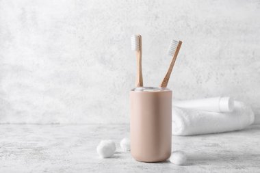 Ahşap diş fırçaları ve arka planda pamuk topları olan tutucu.