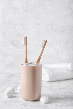 Ahşap diş fırçaları ve arka planda pamuk topları olan tutucu.