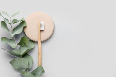 Ahşap diş fırçası ve gri arka planda okaliptüs dalı