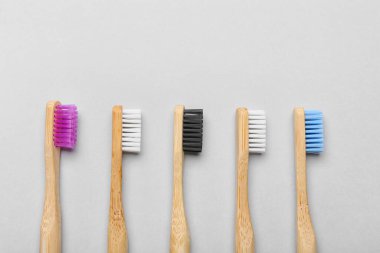 Gri arkaplanda farklı ahşap diş fırçaları, yakın plan.