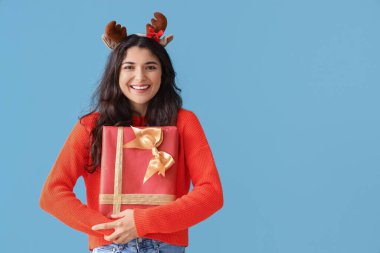 Renkli arkaplanda Noel hediyesi olan güzel bir genç kadın.