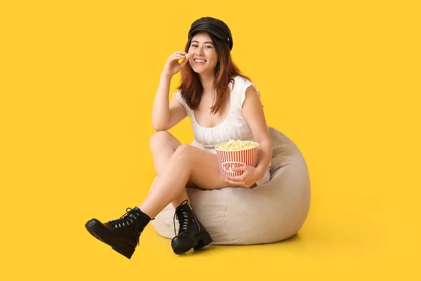 Ung Asiatisk Kvinna Äter Välsmakande Popcorn Bönpåse Stol Gul Bakgrund — Stockfoto