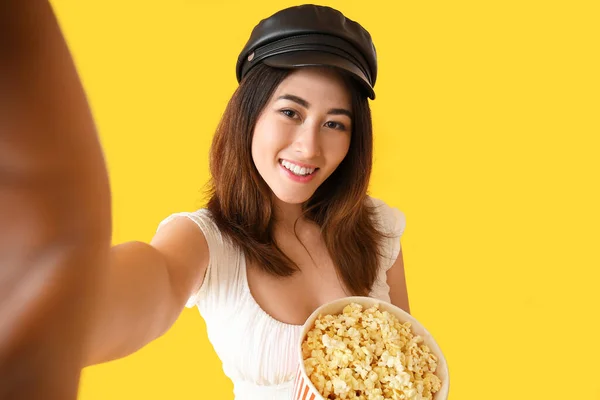 年轻的亚洲女人 带着美味的爆米花 带着黄色背景的自拍 — 图库照片